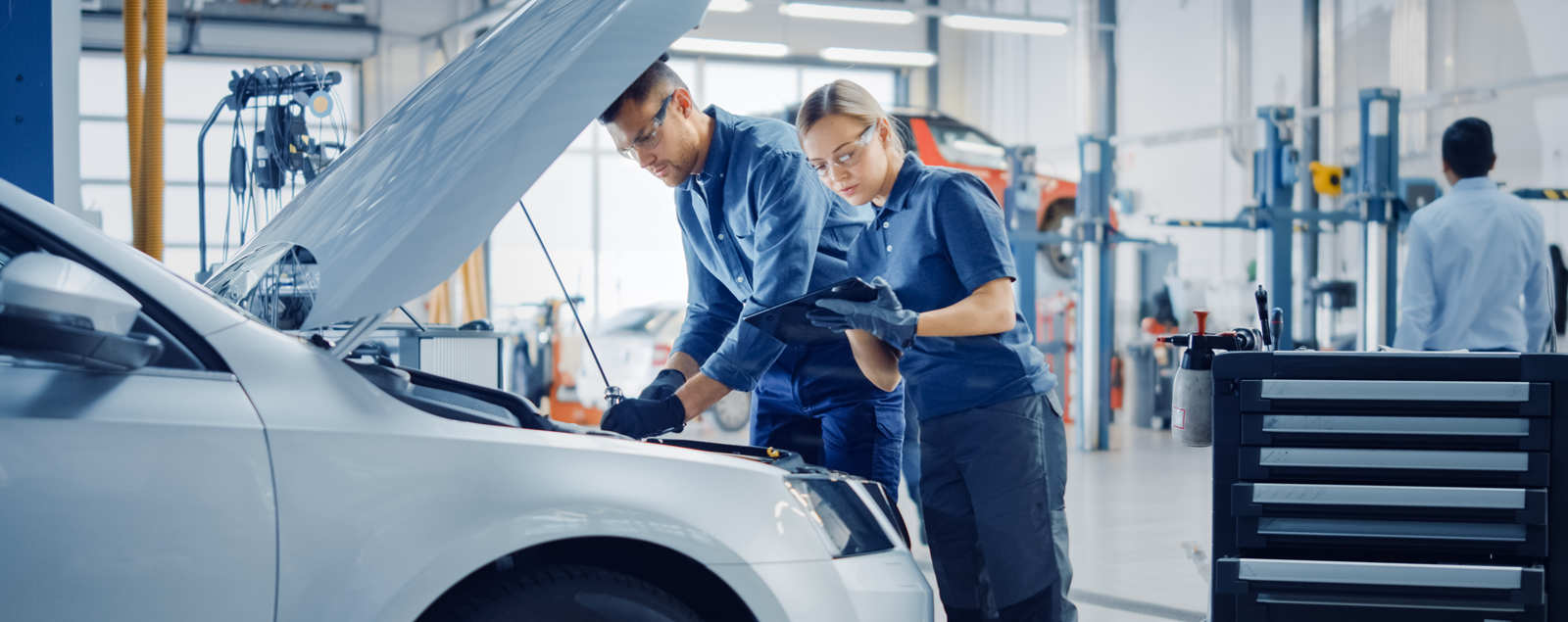 male and female technician in a workshop working on a car