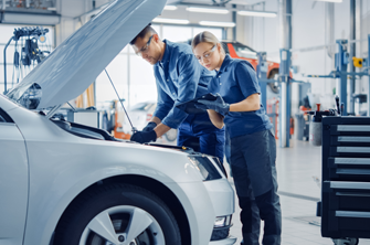 male and female technician in a workshop working on a car