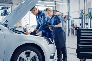 male and female technician in a workshop working on a car