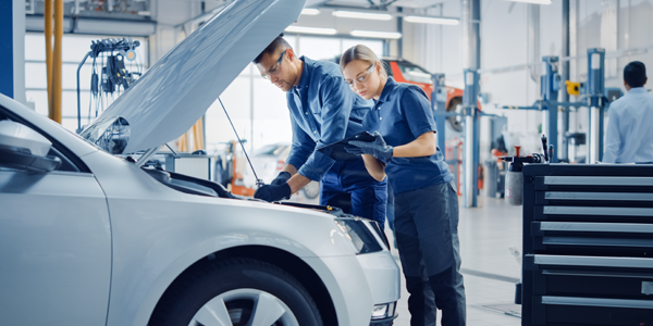 male and female technician in a workshop working on a car