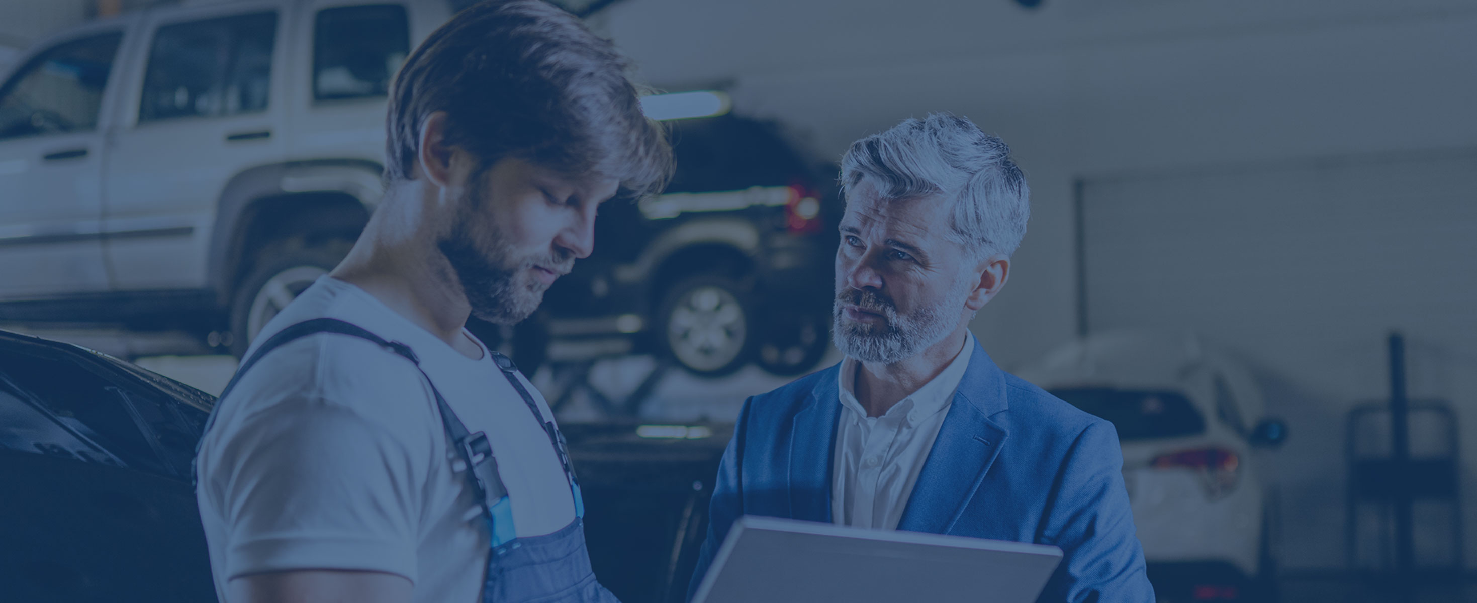 Two men chatting in a workshop with a laptop